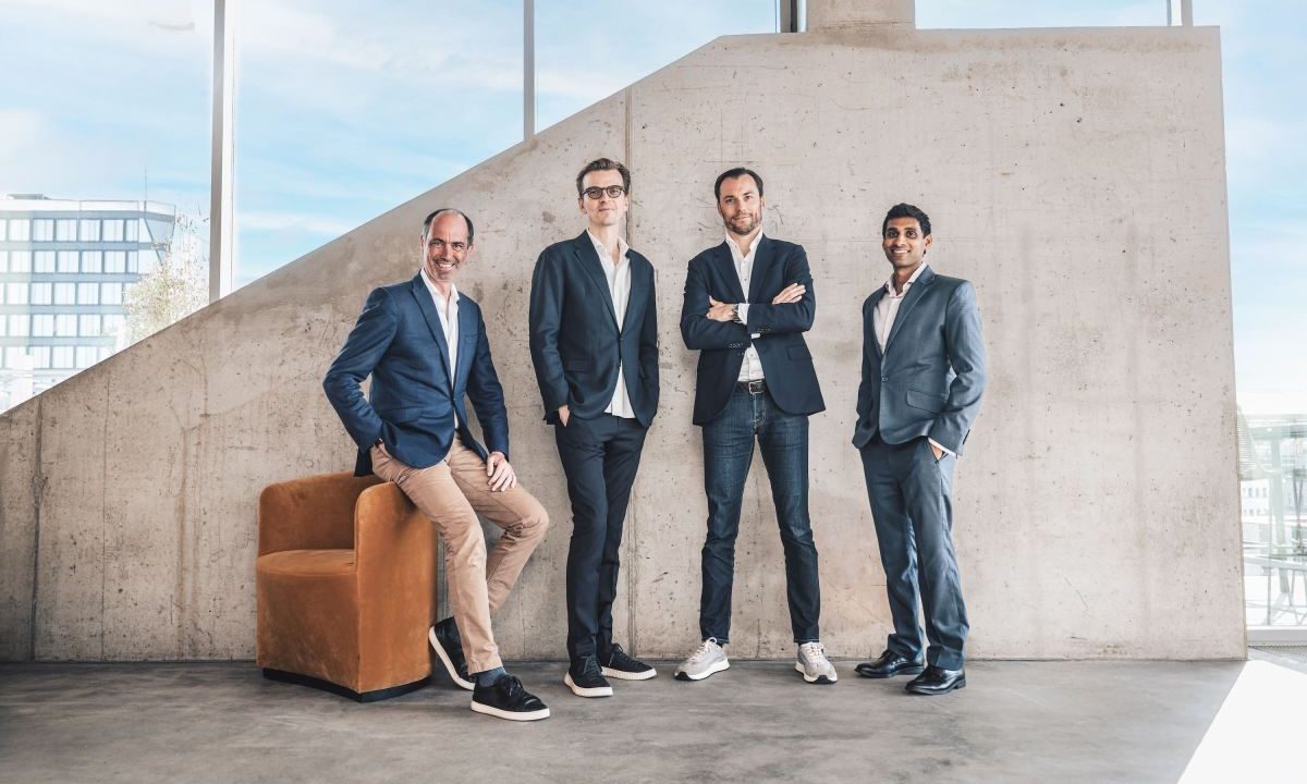 Four men standing in front of a concrete wall.