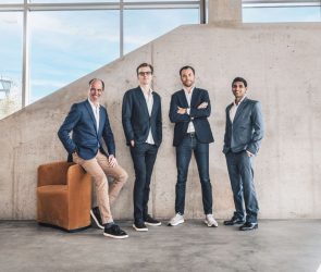 Four men standing in front of a concrete wall.