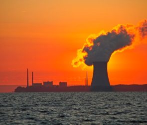 The sun rises behind a nuclear power plant cooling tower.