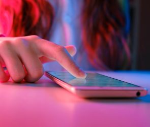 person touching a smartphone laying on a table.