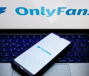 The OnlyFans logo is being displayed on a smartphone screen and on a computer screen