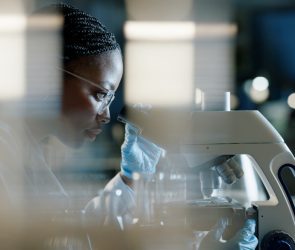 Scientist, microscope and analysis in lab for healthcare and drug discovery