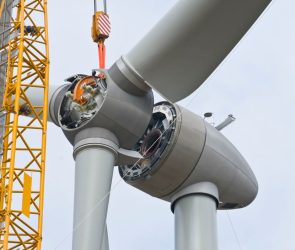 A crane positions the rotor of a wind turbine during construction.