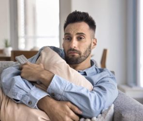 Lonely Young Man Hugging Pillow