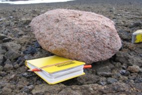 Pink Granite Boulder Next to a Yellow Notebook