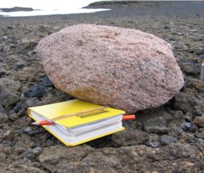 Pink Granite Boulder Next to a Yellow Notebook