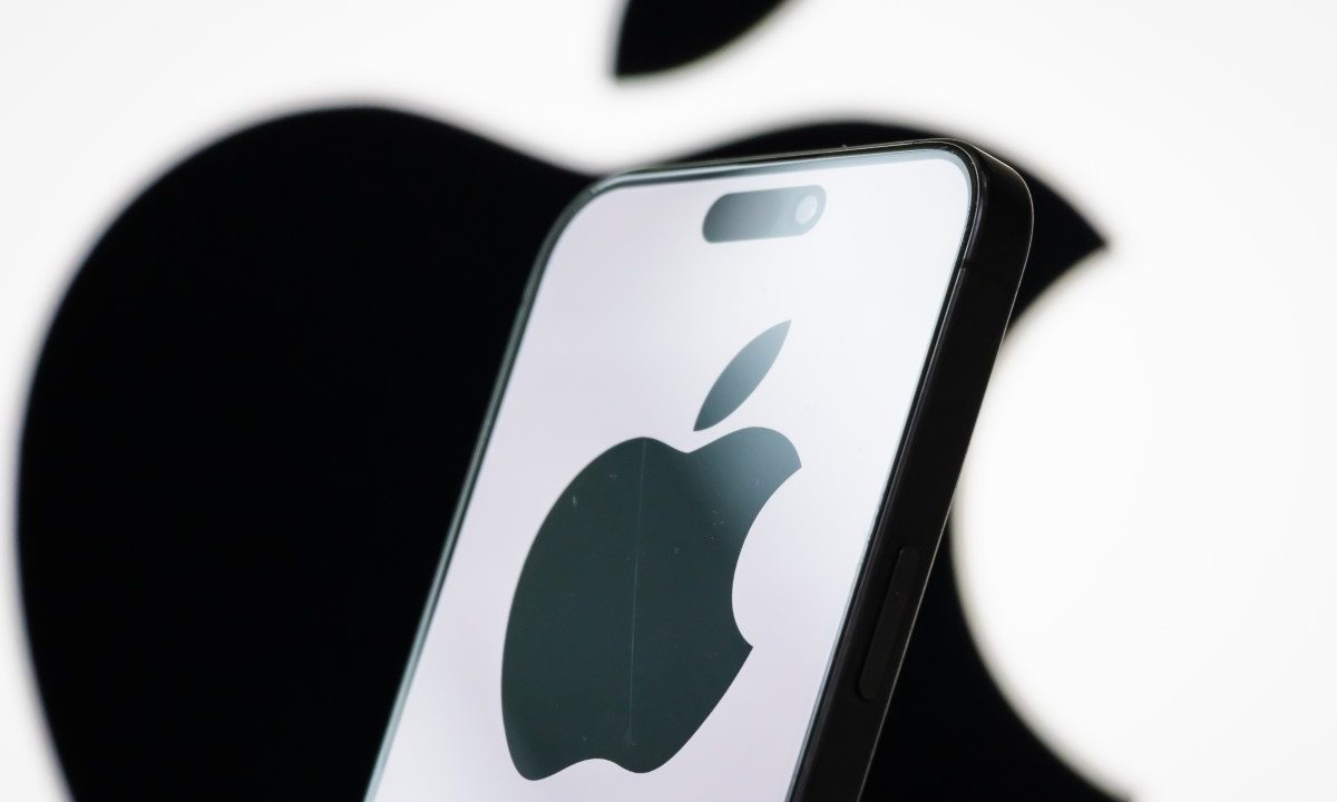 In this photo illustration, the logo of Apple Inc. is displayed on a smartphone screen, with the company's iconic black apple symbol visible in the background.