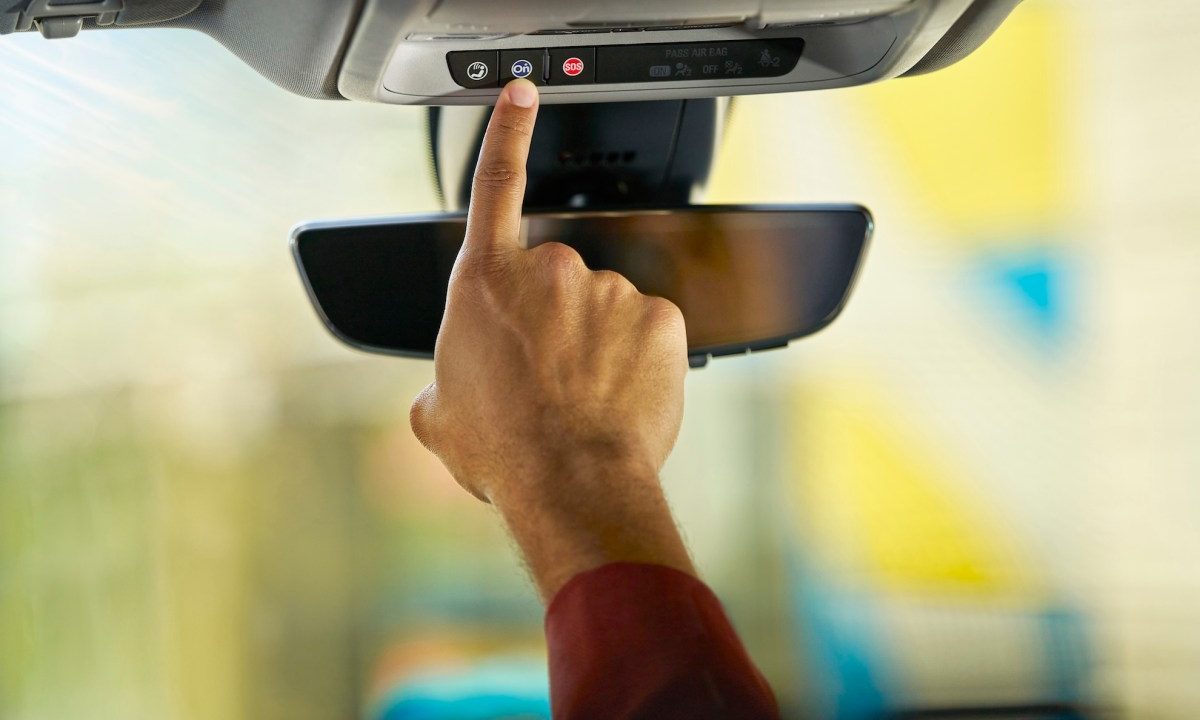 Person pushes the blue OnStar button in a GM vehicle.