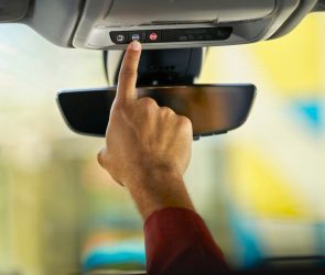 Person pushes the blue OnStar button in a GM vehicle.