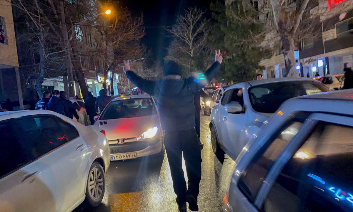 A protester flashes victory signs as traffic slows during demonstrations in Hamedan, Iran, on January 1, 2026.