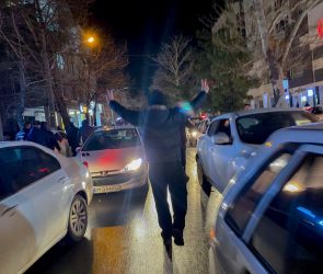 A protester flashes victory signs as traffic slows during demonstrations in Hamedan, Iran, on January 1, 2026.