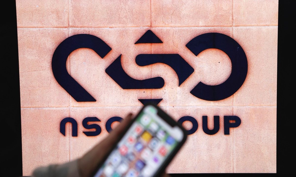 A photographic illustration shows a mobile phone near the NSO Group company logo on February 9, 2022 in the Israeli city of Netanya.