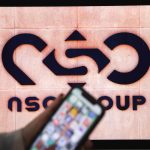 A photographic illustration shows a mobile phone near the NSO Group company logo on February 9, 2022 in the Israeli city of Netanya.