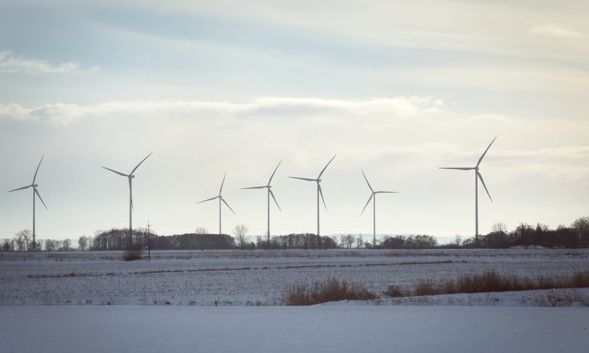 Wind turbines stand across open fields near a railway line in northern Poland, on January 10, 2026.