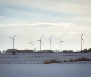 Wind turbines stand across open fields near a railway line in northern Poland, on January 10, 2026.