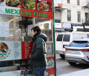 A man places an order at a Mexican food cart.