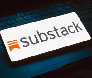 The Substack logo displayed on a phone that is resting on top of a keyboard