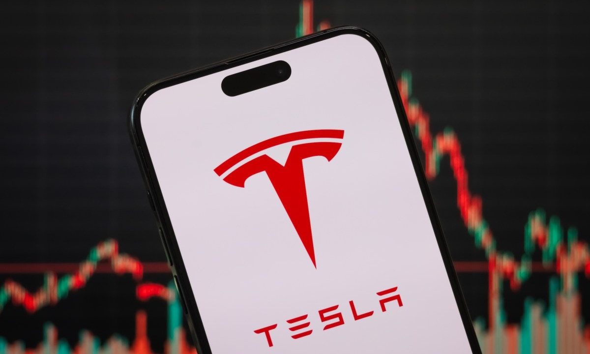 In this photo illustration, the Tesla logo is displayed on a smartphone screen