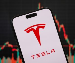 In this photo illustration, the Tesla logo is displayed on a smartphone screen