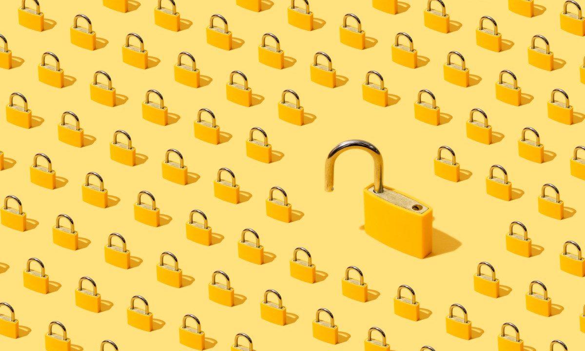 High angle view of many yellow padlocks on yellow background. One of them is open.