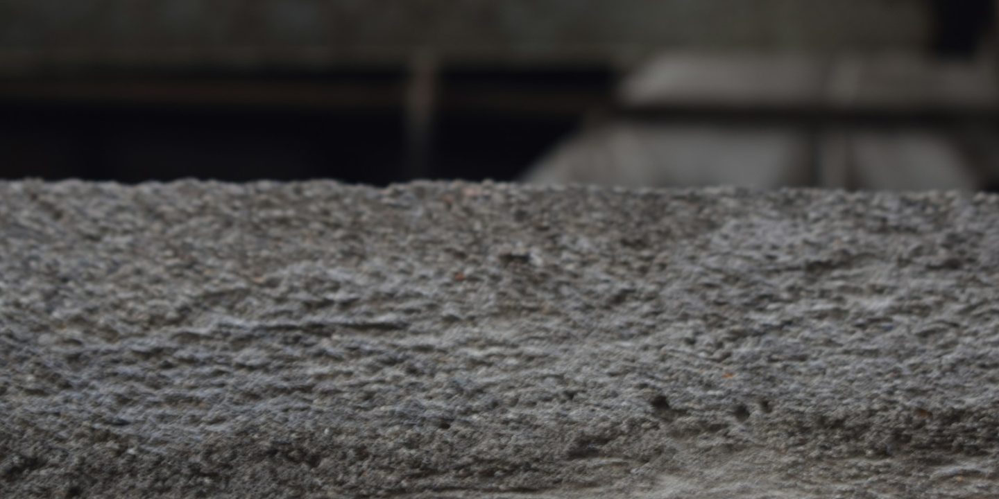 a close up of a cement wall with a building in the background