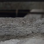 a close up of a cement wall with a building in the background