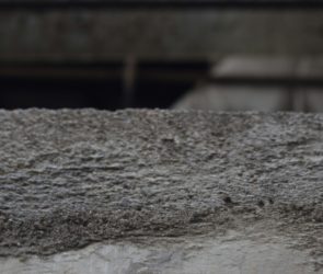 a close up of a cement wall with a building in the background