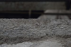 a close up of a cement wall with a building in the background