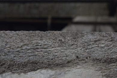 a close up of a cement wall with a building in the background