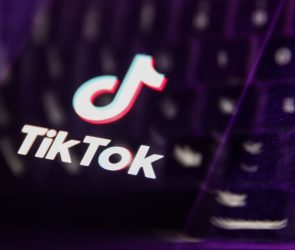 A laptop keyboard and TikTok logo displayed on a phone screen are seen in this multiple exposure illustration.