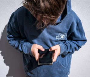 Shows a 14-year-old boy as he looks at social media on his mobile phone.
