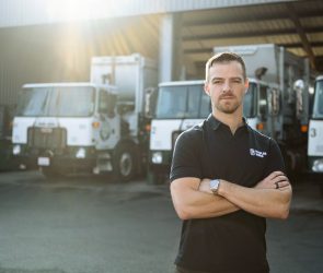 Image of Mark Hoadley, Hauler Hero co-founder and CEO, in front of garbage trucks.