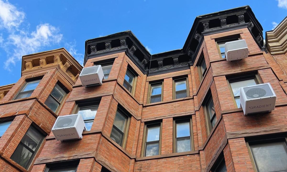 Heat pumps hang on the outside of an apartment building.