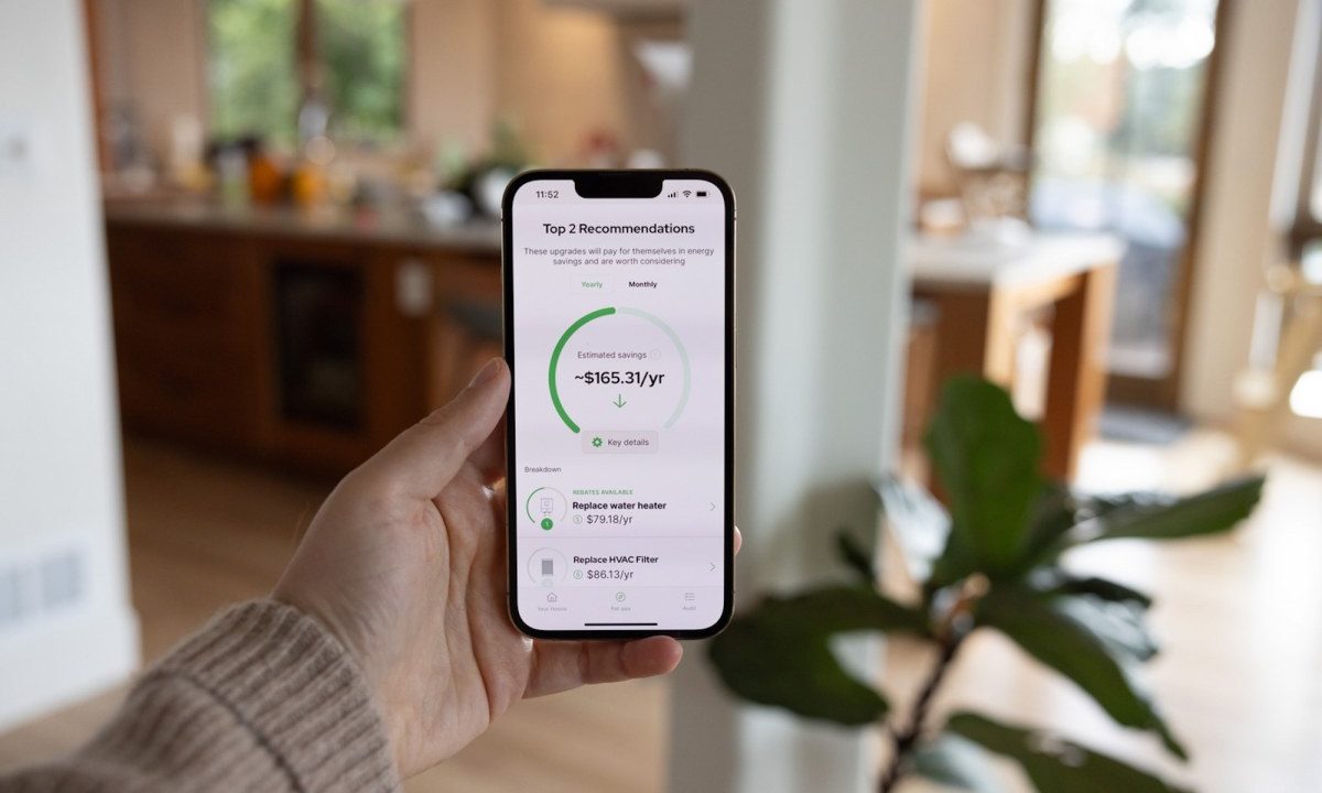 A person holds a phone showing an energy efficiency app.