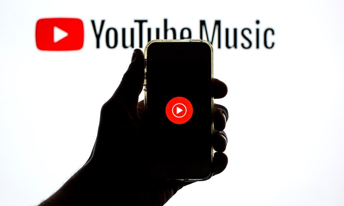 The YouTube Music app seen displayed on a smartphone screen and a YouTube Music logo in the background.