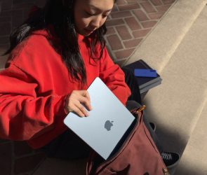 young woman putting Apple MacBook Air into a satchel