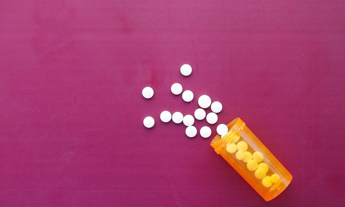 white color medical pills spilling on pink ,