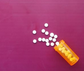 white color medical pills spilling on pink ,