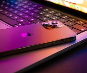 MacBook pro 2021 half open with Iphone 13 lit by retina display