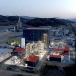 A battery materials factory is lit up at dusk.