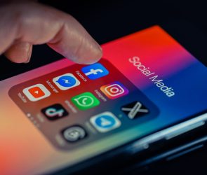 finger pointing to Facebook mobile app displayed on a smartphone screen