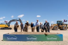 Seven people shovel dirt at a ceremonial groundbreaking.